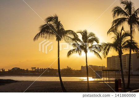 Beautiful colorful sunset sky with silhouette palm trees at the Playa Del Reducto beach in Arrecife, Lanzarote, Canary Islands, Spain Beautiful colorful sunset sky with silhouette palm trees at the Playa Del Reducto beach in Arrecife, Lanzarote, Canary Islands, Spain 141860000