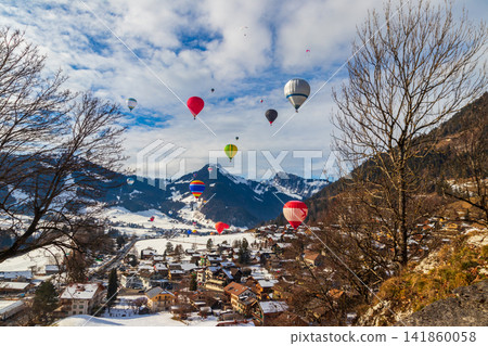 Colorful hot air balloons flying over the winter village of Chateau-d'Oex during the International Balloon Festival in the Swiss Alps, Switzerland Colorful hot air balloons flying over the winter village of Chateau-d'Oex during the International Balloon Festival in the Swiss Alps, Switzerland 141860058
