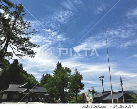 Contrails in the blue sky. White clouds and green trees stand out against the blue sky. Contrails in the blue sky. White clouds and green trees stand out against the blue sky. 141860194