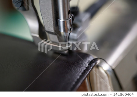 A close-up of leather crafting: sewing leather with industrial sewing machines. A close-up of leather crafting: sewing leather with industrial sewing machines. 141860404
