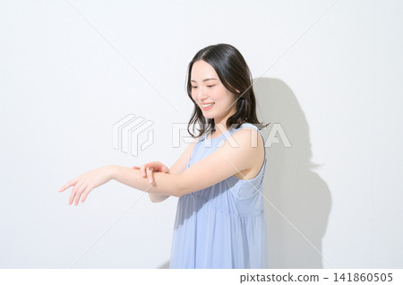 一張美麗的日本女性照片,她正在白色背景上的手臂上塗抹防曬霜。 一張美麗的日本女性照片,她正在白色背景上的手臂上塗抹防曬霜。 141860505