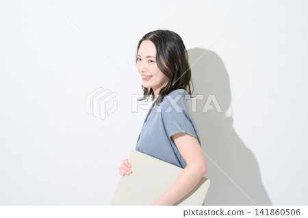一位日本女性面帶微笑，手持筆記型電腦，背景為白色。 141860506