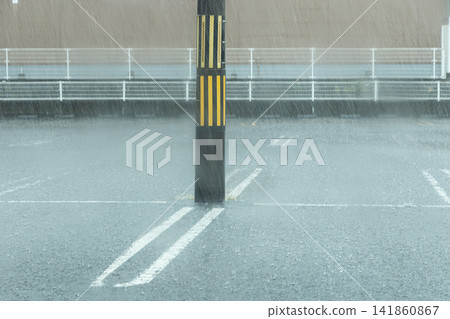 Heavy rain lashes the parking lot, obscuring the white lines and utility poles. Heavy rain lashes the parking lot, obscuring the white lines and utility poles. 141860867