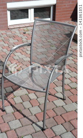 Weathered Metal Chair In Peaceful Backyard Corner. Quiet Spot With Curved Armrest And Morning Sunlight Touch Weathered Metal Chair In Peaceful Backyard Corner. Quiet Spot With Curved Armrest And Morning Sunlight Touch 141861851