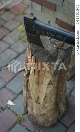 Late Afternoon Scene With Weathered Axe Embedded In Vintage Wooden Block On Cobblestone Patio Late Afternoon Scene With Weathered Axe Embedded In Vintage Wooden Block On Cobblestone Patio 141861862