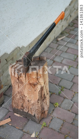 Homeowner Prepares Firewood Outside. Practical Suburban Task Involving Axe And Bark On Brick Pathway Homeowner Prepares Firewood Outside. Practical Suburban Task Involving Axe And Bark On Brick Pathway 141861863