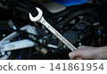 Closeup Hands Holding Wrench, Motorcycle Engine, Gritty Roadside Repair Scene With Oil Smudges, Focused Finger 141861954