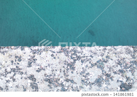 Top view of turquoise water beside a rough weathered concrete edge, creating an abstract geometric composition with contrasting textures, minimal design and refreshing aquatic tones Top view of turquoise water beside a rough weathered concrete edge, creating an abstract geometric composition with contrasting textures, minimal design and refreshing aquatic tones 141861981