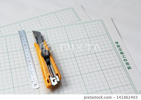Two sheets of construction paper, a ruler, and a cutter. Two sheets of construction paper, a ruler, and a cutter. 141862483