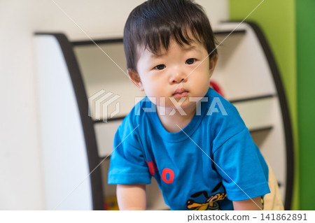A Japanese baby boy leaning against a pink soft block in the kids' room. A Japanese baby boy leaning against a pink soft block in the kids' room. 141862891
