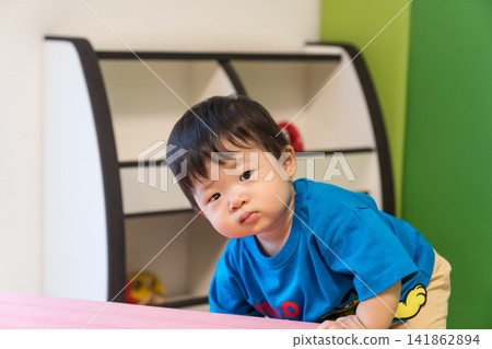 A Japanese baby boy leaning against a pink soft block in the kids' room. A Japanese baby boy leaning against a pink soft block in the kids' room. 141862894