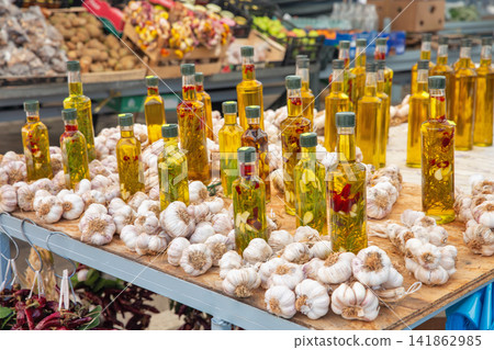 Bottled olive oil and garlic bulbs at market stall, Croatia. Bottled olive oil and garlic bulbs at market stall, Croatia. 141862985