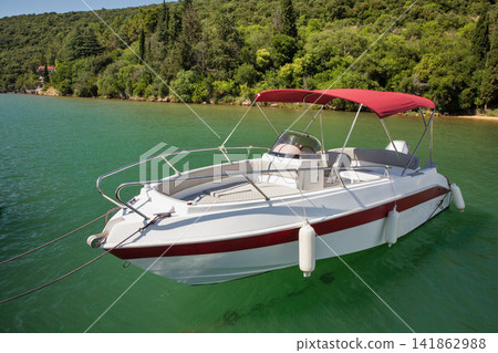 Modern motorboat with red canopy moored in Lim Fjord, Croatia. Modern motorboat with red canopy moored in Lim Fjord, Croatia. 141862988