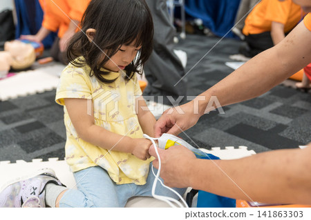 一名日本小女孩在緊急救生體驗活動中觸摸了AED（自動體外心臟去顫器）。 141863303