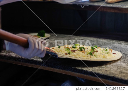 Chef Preparing Uncooked Artisan White Pizza with Mozzarella Broccoli and Mushrooms in Restaurant Kitchen Chef Preparing Uncooked Artisan White Pizza with Mozzarella Broccoli and Mushrooms in Restaurant Kitchen 141863817