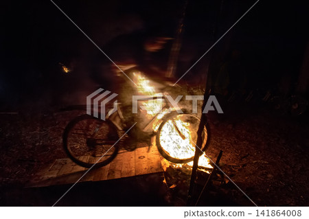 Cyclists jump on a Bicycle over a fire at night Cyclists jump on a Bicycle over a fire at night 141864008
