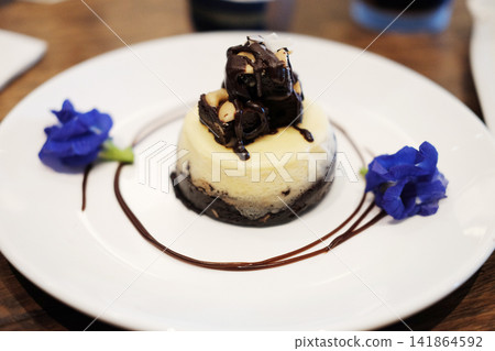 Fresh mini chocolate cheesecake with edible flowers in white plate Fresh mini chocolate cheesecake with edible flowers in white plate 141864592