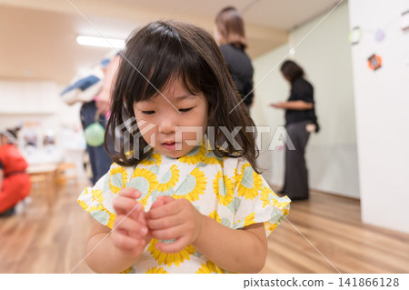 A young Japanese girl wearing a jinbei (traditional Japanese summer wear) with a sunflower pattern. A young Japanese girl wearing a jinbei (traditional Japanese summer wear) with a sunflower pattern. 141866128