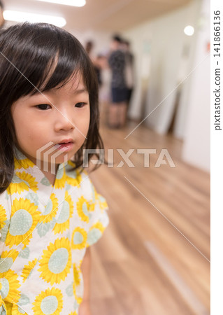 A young Japanese girl wearing a jinbei (traditional Japanese summer wear) with a sunflower pattern. A young Japanese girl wearing a jinbei (traditional Japanese summer wear) with a sunflower pattern. 141866136
