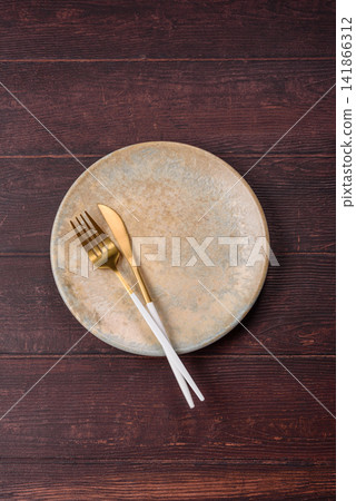 An empty round ceramic plate on a dark, textured brown background. An empty round plate An empty round ceramic plate on a dark, textured brown background. An empty round plate 141866312