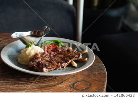 Grilled Beef Steak Served with Mashed Potatoes, Roasted Tomato, Green Beans, and Brown Gravy on a Rustic Wooden Table Grilled Beef Steak Served with Mashed Potatoes, Roasted Tomato, Green Beans, and Brown Gravy on a Rustic Wooden Table 141866428