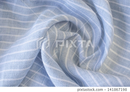 Draped light blue fabric with white stripes. Natural linen fabric. Blue and white striped linen fabric with soft folds. Draped light blue fabric with white stripes. Natural linen fabric. Blue and white striped linen fabric with soft folds. 141867198