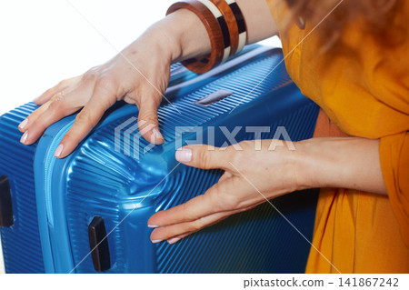 Close Up of Woman Inspecting Dented Blue Suitcase Close Up of Woman Inspecting Dented Blue Suitcase 141867242