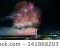 A spectacular fireworks display with multiple large bursts of fireworks overlapping. 141868203