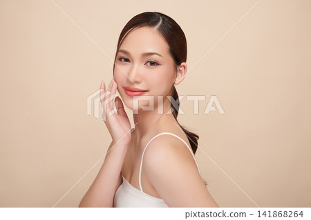 A beautiful young Asian woman with clean, fresh skin against a beige background. Skincare, facial treatment, cosmetology, beauty, and spa. An elegant portrait of an Asian woman. A beautiful young Asian woman with clean, fresh skin against a beige background. Skincare, facial treatment, cosmetology, beauty, and spa. An elegant portrait of an Asian woman. 141868264