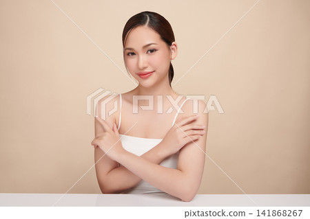 A beautiful young Asian woman with clean, fresh skin against a beige background. Skincare, facial treatment, cosmetology, beauty, and spa. An elegant portrait of an Asian woman. A beautiful young Asian woman with clean, fresh skin against a beige background. Skincare, facial treatment, cosmetology, beauty, and spa. An elegant portrait of an Asian woman. 141868267