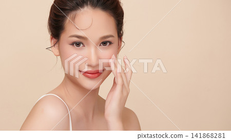 A beautiful young Asian woman with clean, fresh skin against a beige background. Skincare, facial treatment, cosmetology, beauty, and spa. An elegant portrait of an Asian woman. A beautiful young Asian woman with clean, fresh skin against a beige background. Skincare, facial treatment, cosmetology, beauty, and spa. An elegant portrait of an Asian woman. 141868281