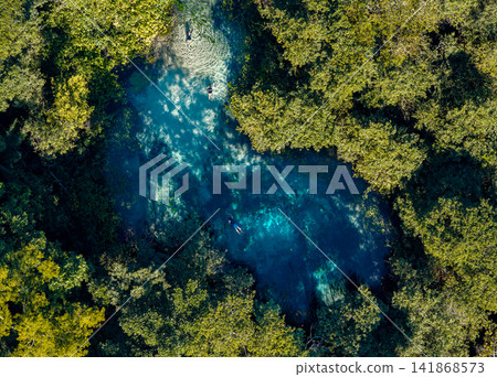 Aerial view of a secluded blue spring nestled in a forest near Bonito, Brazil. Aerial view of a secluded blue spring nestled in a forest near Bonito, Brazil. 141868573