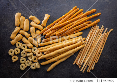 Assorted Breadsticks and Savory Crackers on Dark Slate Background for Snacks and Appetizers Assorted Breadsticks and Savory Crackers on Dark Slate Background for Snacks and Appetizers 141868609