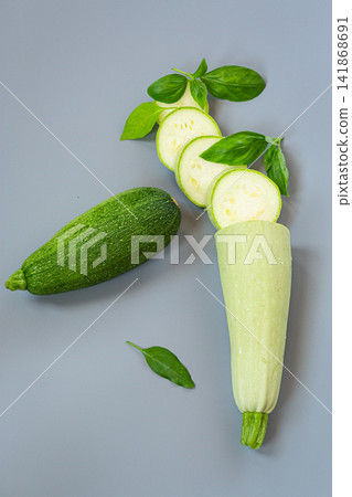Fresh zucchini with sliced courgette on gray background with basil Fresh zucchini with sliced courgette on gray background with basil 141868691