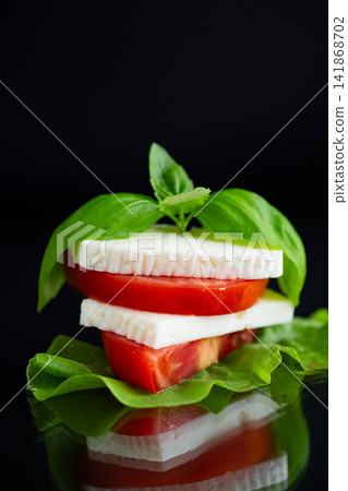 Traditional feta cheese appetizer with basil on black reflective background Traditional feta cheese appetizer with basil on black reflective background 141868702