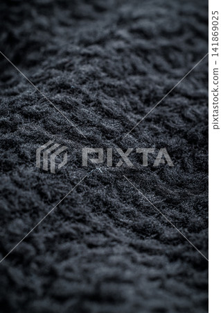 The texture of a soft black fleece fabric with visible fibers and folds The texture of a soft black fleece fabric with visible fibers and folds 141869025