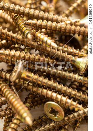 A close-up of a pile of wooden screws with gold-colored heads, scattered randomly on a background 141869080