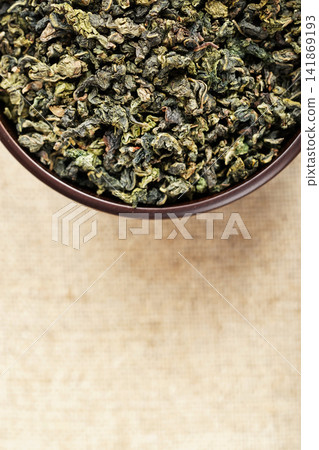 Top view closeup dark wood cup full of loose tea on natural fabric Top view closeup dark wood cup full of loose tea on natural fabric 141869193