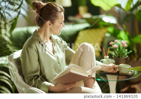 Woman Reaching for Tea During a Peaceful Reading Session Woman Reaching for Tea During a Peaceful Reading Session 141869320