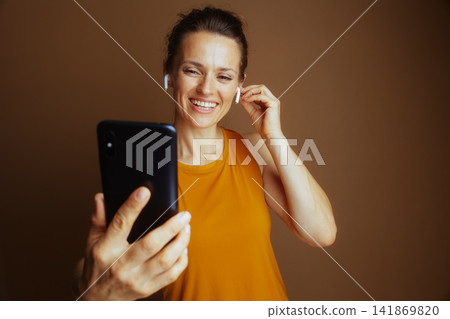 Woman Adjusting Earbud While Using Phone Woman Adjusting Earbud While Using Phone 141869820