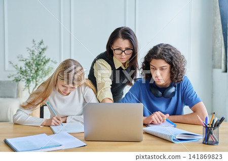 Two smiling teen students with laptop at desk Two smiling teen students with laptop at desk 141869823