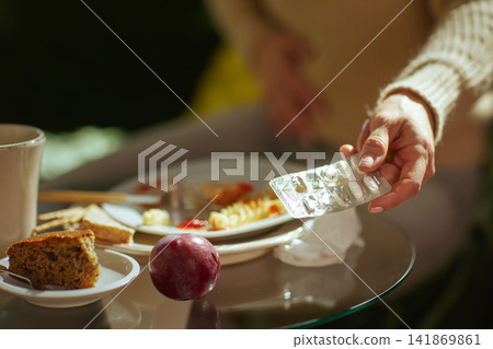 Hand Holding Digestive Pills Over Leftover Food Hand Holding Digestive Pills Over Leftover Food 141869861