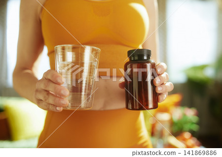 Woman Taking Daily Supplements with Water 141869886