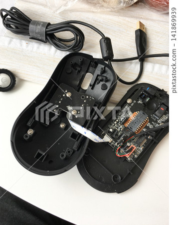 Disassembled black computer mouse showing internal circuit board and cable. Disassembled black computer mouse showing internal circuit board and cable. 141869939