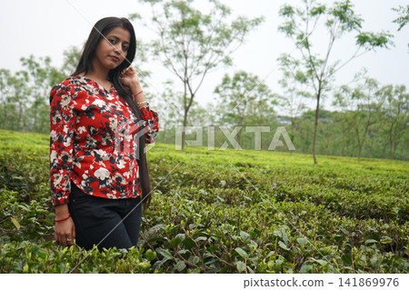Beautiful Indian woman posing amidst a lush green tea garden plantation in North Bengal Beautiful Indian woman posing amidst a lush green tea garden plantation in North Bengal 141869976