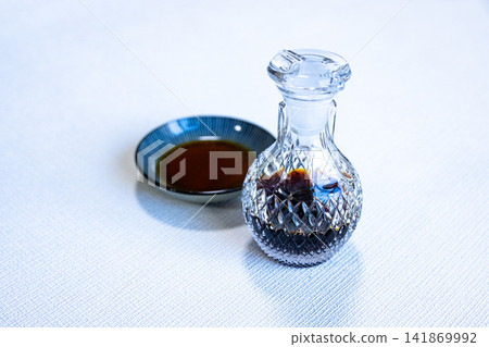 一個玻璃醬油瓶和一個小圓盤放在白色背景上。 一個玻璃醬油瓶和一個小圓盤放在白色背景上。 141869992