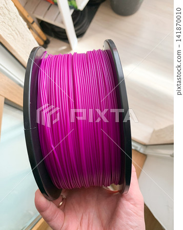 Bright pink 3D printing filament spool held in a hand for project creation Bright pink 3D printing filament spool held in a hand for project creation 141870010
