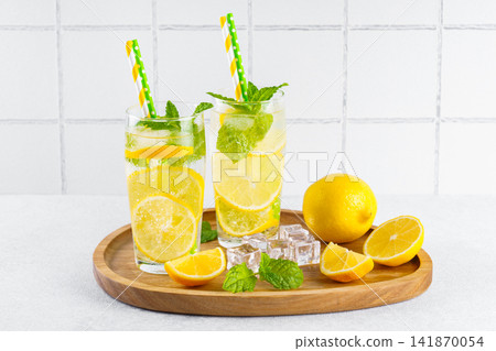 Refreshing homemade lemonade with fresh lemon, mint, ice and condensation served on wooden tray Refreshing homemade lemonade with fresh lemon, mint, ice and condensation served on wooden tray 141870054