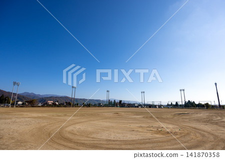 A dirt field stretches out under a clear blue sky. A dirt field stretches out under a clear blue sky. 141870358