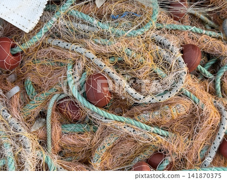 Fishing nets with ropes and floats create a textured background for marine-themed designs Fishing nets with ropes and floats create a textured background for marine-themed designs 141870375